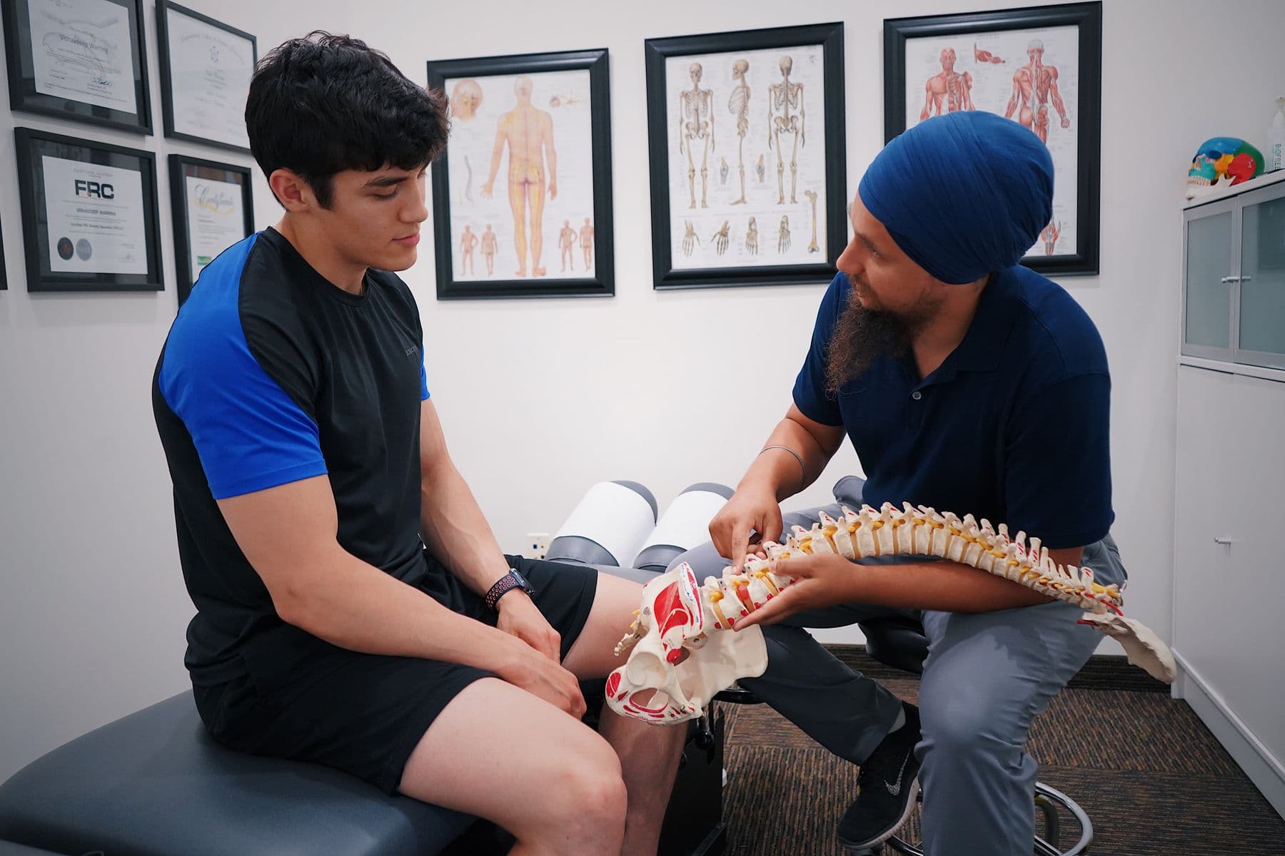 Doctor explaining a spine model to a patient in a chiropractic office