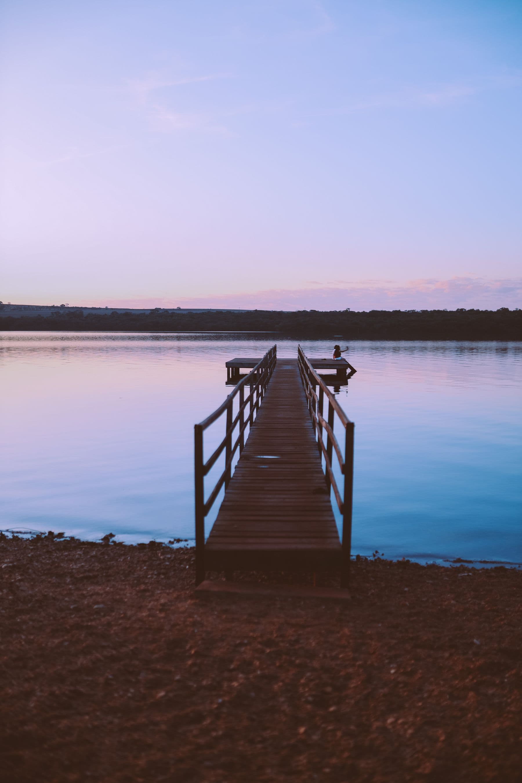 Wooden pier reaching into a calm lake at dawn